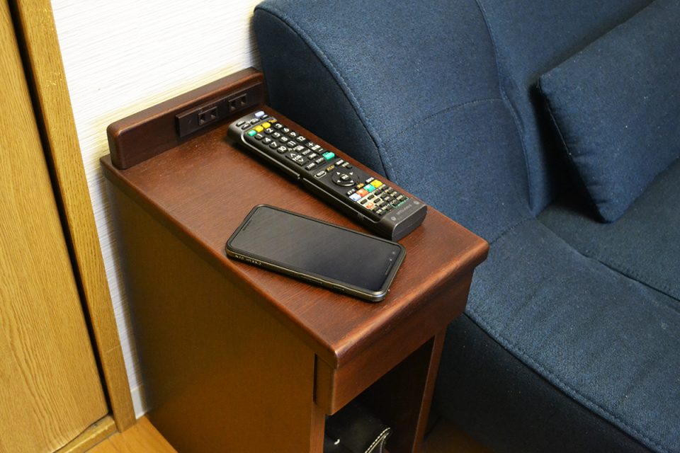 ナイトテーブルの上に置いたスマホとリモコン